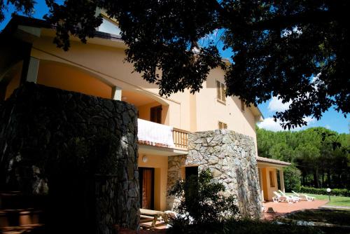 uma casa grande com uma parede de pedra ao lado em Poggio Guicciardino em Venturina Terme