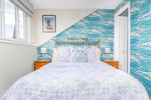 a bedroom with a bed and a blue and white wall at Bramblewick in Whitby