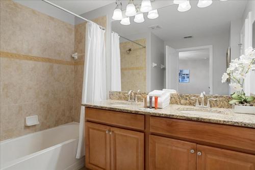 y baño con bañera, lavabo y espejo. en 4 Bedrooms 3 Bathrooms Paradise Palms 8974 Mp, en Orlando