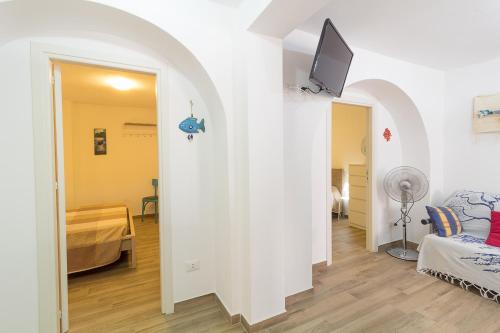 een woonkamer met een bank en een tv aan de muur bij Apartment Veterani in Cefalù