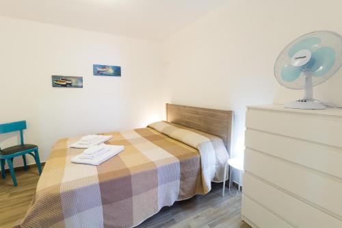 een slaapkamer met een bed en een dressoir met een ventilator bij Apartment Veterani in Cefalù