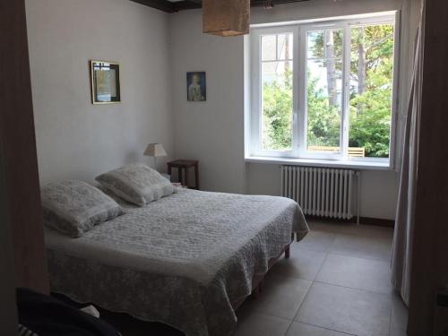 um quarto com uma cama e uma grande janela em Maison lumineuse 2mn plage et village de Morgat em Crozon