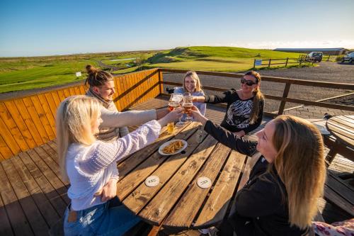 a group of women sitting around a wooden table with drinks at Hótel Eyjafjallajökull in Hvolsvöllur