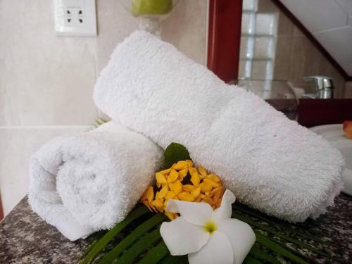 a white towel on top of a counter with flowers at Badamier Self-Catering in La Digue