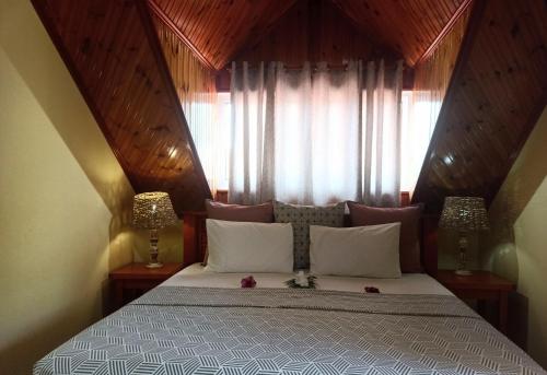a bedroom with a bed with two lamps and a window at Badamier Self-Catering in La Digue