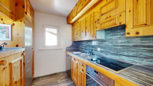 a kitchen with wooden cabinets and a sink at Abitaziun Curtins 1 6 - La Punt Chamues-ch in La Punt-Chamues-ch