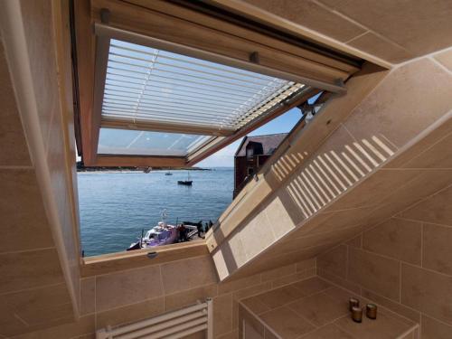 a window in a bathroom with a boat in the water at Quayside Cottage in North Berwick