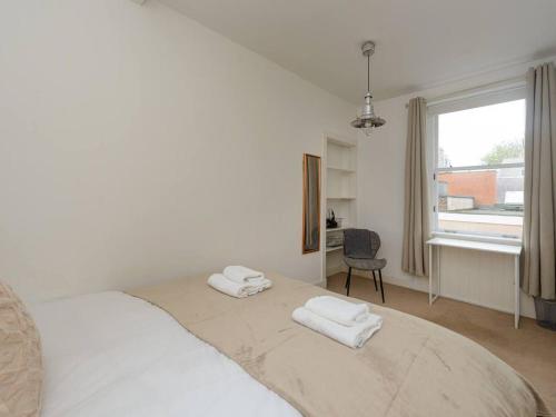 a white bedroom with a bed with two towels on it at Pebbles Apartment in North Berwick