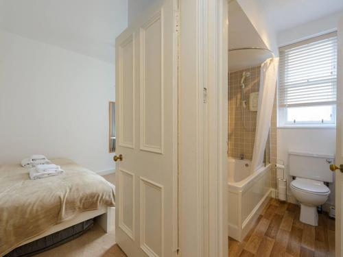 a bathroom with a bed and a tub and a toilet at Pebbles Apartment in North Berwick