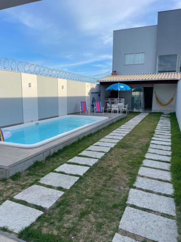 Un patio trasero con piscina y una casa. en Duplex Praia do Bosque, en Guriri