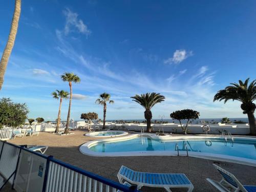 uma piscina com palmeiras e uma praia em Casaloé em Puerto del Carmen