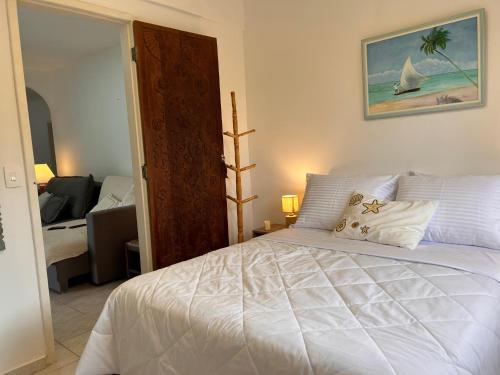 a bedroom with a bed with a white bedspread and a window at Casa Amarela in Angra dos Reis