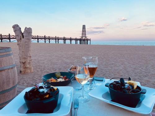 a table with two bowls of food and wine on the beach at Les Voiles Blanches T2 luxe à 100m de la plage in Leucate
