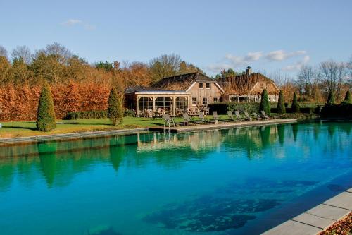 ein Haus mit einem Teich davor in der Unterkunft Landhuis Hotel de Hilkensberg in Broekhuizen