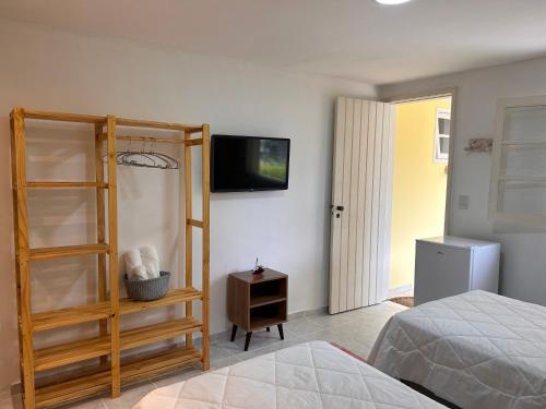 a bedroom with a bed and a tv on the wall at Casa Amarela in Angra dos Reis