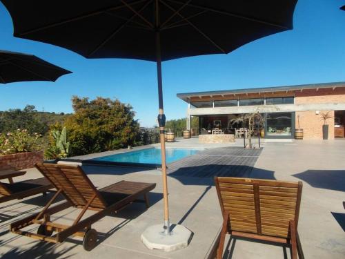 a couple of chairs and an umbrella next to a pool at Fijnbosch Self Catering Chalet in Jeffreys Bay