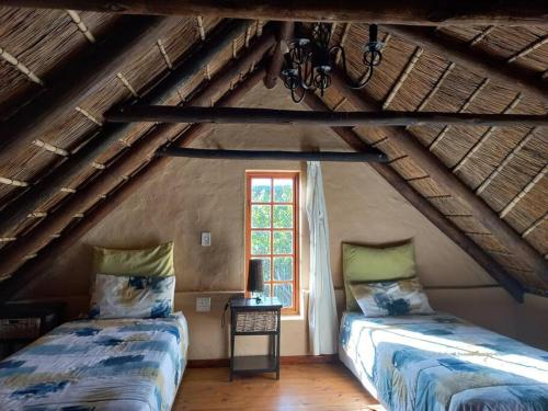 a attic room with two beds and a window at Fijnbosch Self Catering Chalet in Jeffreys Bay