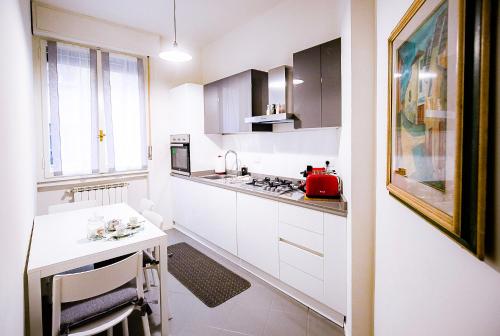 a kitchen with white cabinets and a table with a red appliance at Acacia Firenze - Avocado in Florence