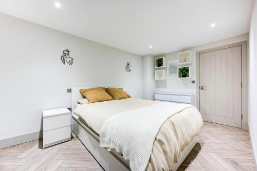 a white bedroom with a bed and a white door at Lovely 1-bed flat with a balcony & garden access in London