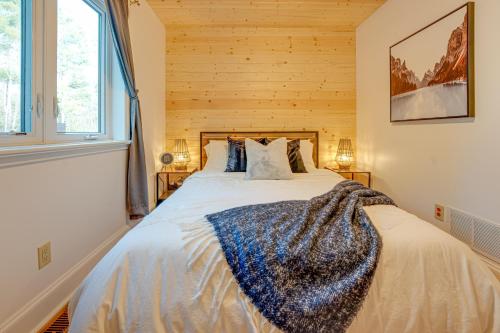 a bedroom with a bed with a wooden wall at Waterfront Muskoka Cottage with Hot Tub & Game Room in Bracebridge