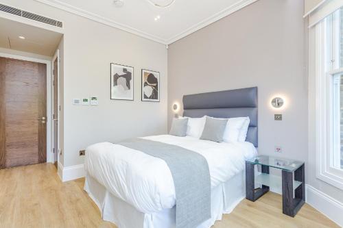 a white bedroom with a large bed and a table at LuxLet Apartments - Heart of Hampstead, London in London