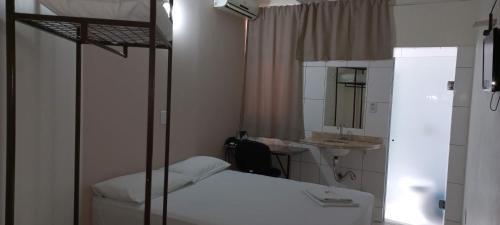 a bedroom with a bed and a sink and a mirror at Hotel Romanville in Chapecó