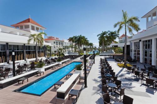 un complejo con piscina, sillas y palmeras en Riu Palace Mexico - All Inclusive en Playa del Carmen