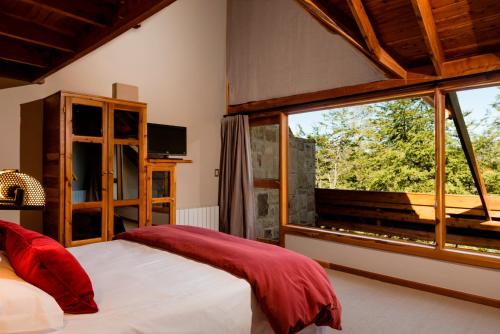 a bedroom with a bed and a large window at Hosteria La Camila in Villa La Angostura