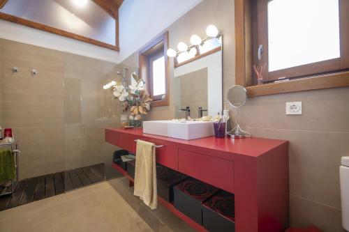 La salle de bains est pourvue d'un lavabo rouge et d'un miroir. dans l'établissement Catalunya Casas Infinity pool and views 20min to Barcelona, à Torrelles de Llobregat