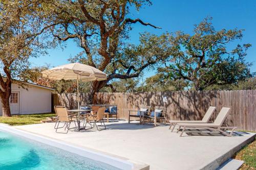 un patio con sillas y una sombrilla junto a la piscina en The Mathis House, en Rockport