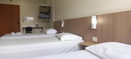 duas camas num quarto de hospital com lençóis brancos em Hotel Romanville em Chapecó