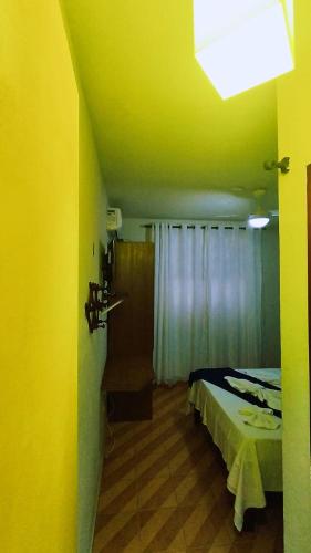 a bedroom with a bed and a yellow wall at Pousada Do Suiá in Arraial do Cabo