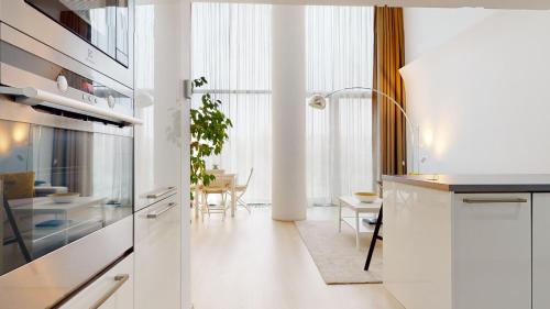 Eurovea Apartments في براتيسلافا: مطبخ مع دواليب بيضاء وغرفة طعام