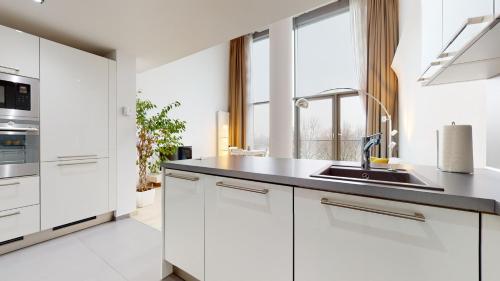 Eurovea Apartments في براتيسلافا: مطبخ مع دواليب بيضاء ومغسلة