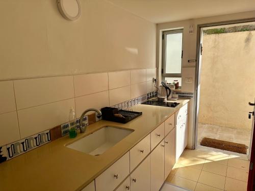 a white kitchen with a sink and a window at Ein Hod - Artists Village in ‘En Hod