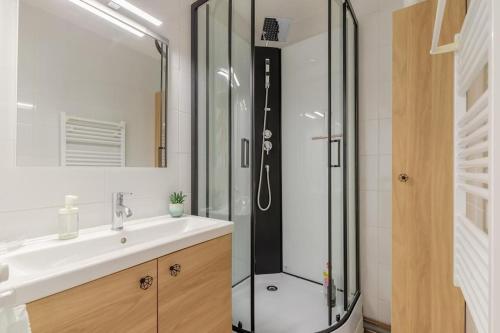 La salle de bains est pourvue d'une douche et d'un lavabo blanc. dans l'établissement LA ROSE DE L OCEAN, à Saint-Hilaire-de-Riez