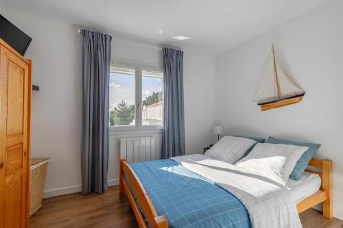 - une chambre avec un lit bleu et blanc et une fenêtre dans l'établissement LA ROSE DE L OCEAN, à Saint-Hilaire-de-Riez