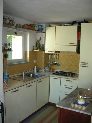 a kitchen with white cabinets and a sink at villetta a 100 mt dalla spiaggia in Eraclea Minoa