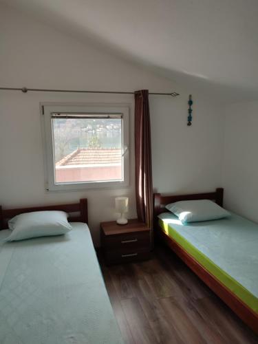 two beds in a room with a window at Mystras Apartments in Kotor