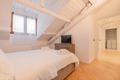 a white bedroom with a large bed and a television at Brera Flat Near Duomo in Milan