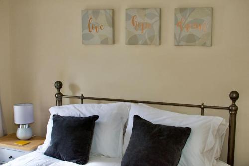a bed with two pillows and three pictures on the wall at Cottage in Framlingham in Framlingham