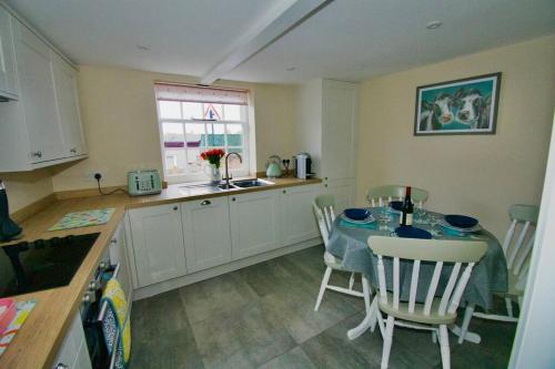 cocina con mesa, sillas y fregadero en Cottage in Framlingham en Framlingham