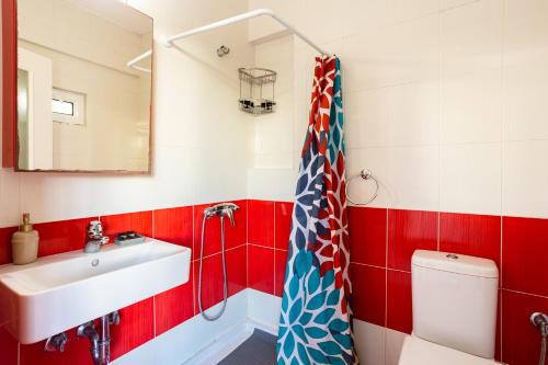 een rood-witte badkamer met een wastafel en een toilet bij Serenity and Relaxing Studio in Kalamata