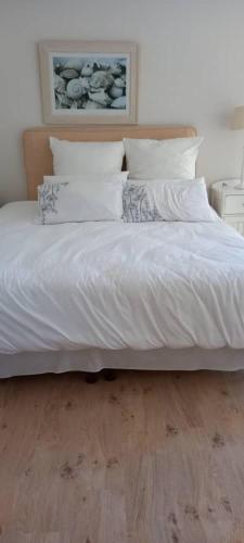 a bed with white sheets and pillows on a wooden floor at Cle’s seaview in Langstrand