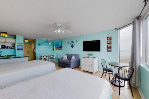 a bedroom with two beds and a tv and a table at The Top of the Gulf #612 in Panama City Beach