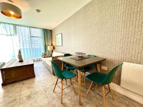a living room with a table and green chairs at Stunning 2 bedroom Apartment inc Free Parking - 1 Minute walk to Poole Quay - Great Location - Free Parking - Fast WiFi - Smart TV - Newly decorated - sleeps up to 4 - Close to Poole & Bournemouth & Sandbanks in Poole