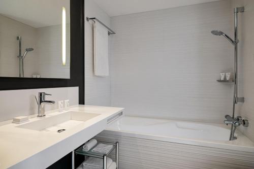 a white bathroom with a sink and a tub at AC Hotel by Marriott Nice in Nice