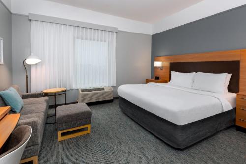 Habitación de hotel con cama grande y sofá en TownePlace Suites Buffalo Airport, en Cheektowaga