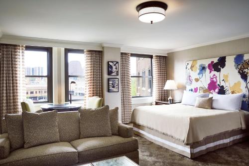 ein Schlafzimmer mit einem Bett, einem Sofa und Fenstern in der Unterkunft The Raphael Hotel, Autograph Collection in Kansas City