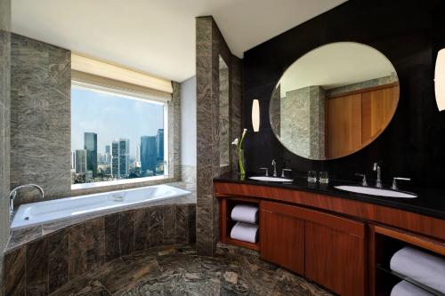 ein Badezimmer mit einer Badewanne und einem großen Spiegel in der Unterkunft The Ritz-Carlton Jakarta, Pacific Place in Jakarta